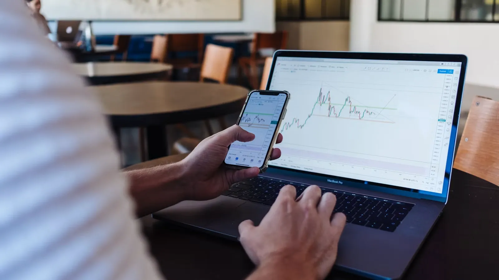 Investor replicating another trader's positions using a smartphone and laptop