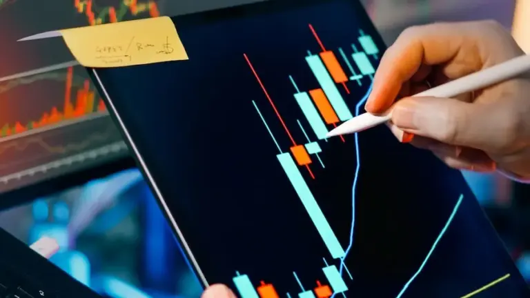 A trader analysing market charts on a tablet and monitor