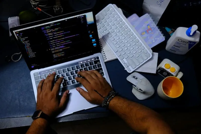 Hands typing on a laptop showing code