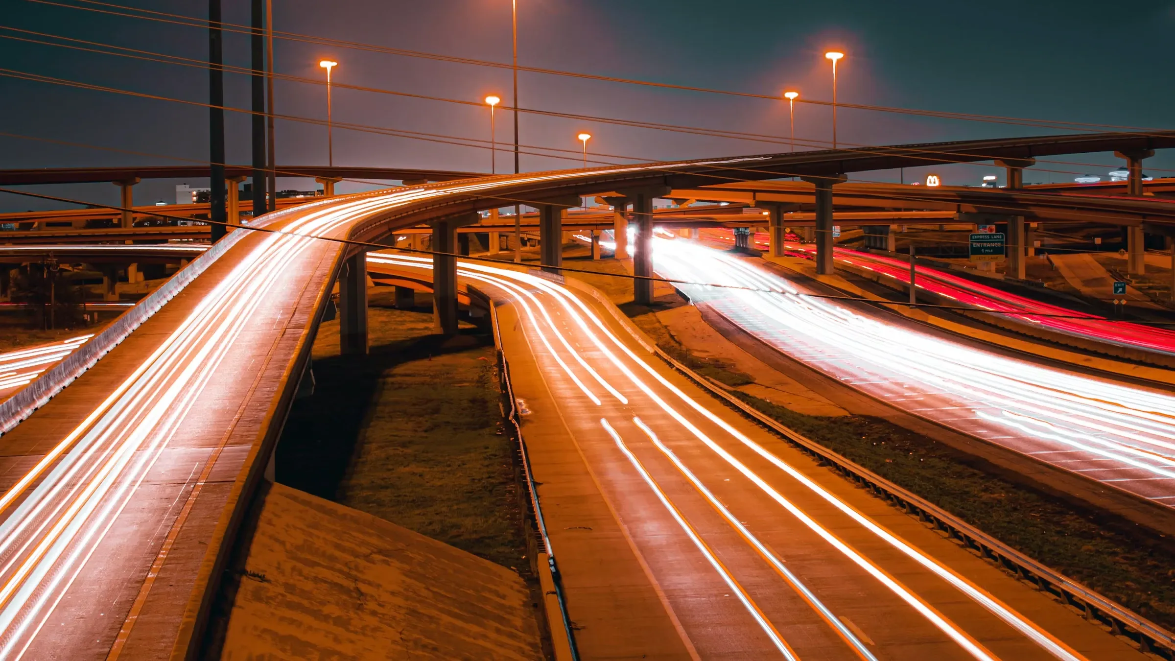A long-exposure photo of a highway at night with light trails
