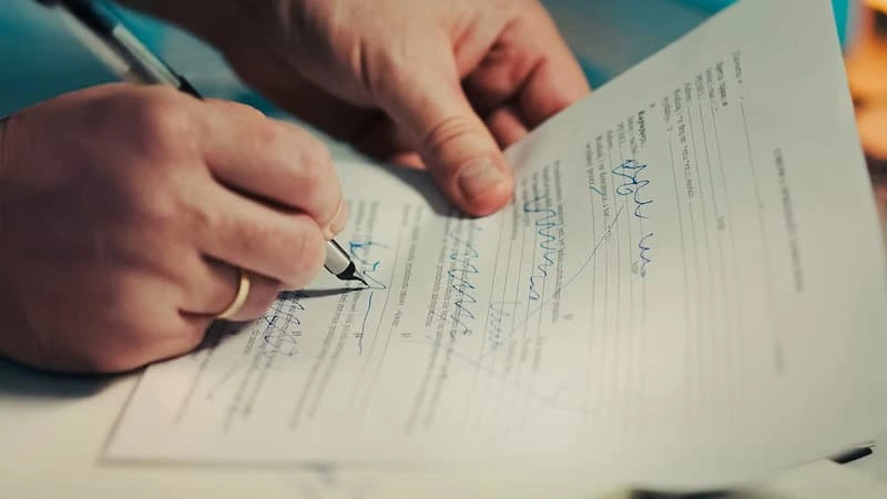 Hands signing a document
