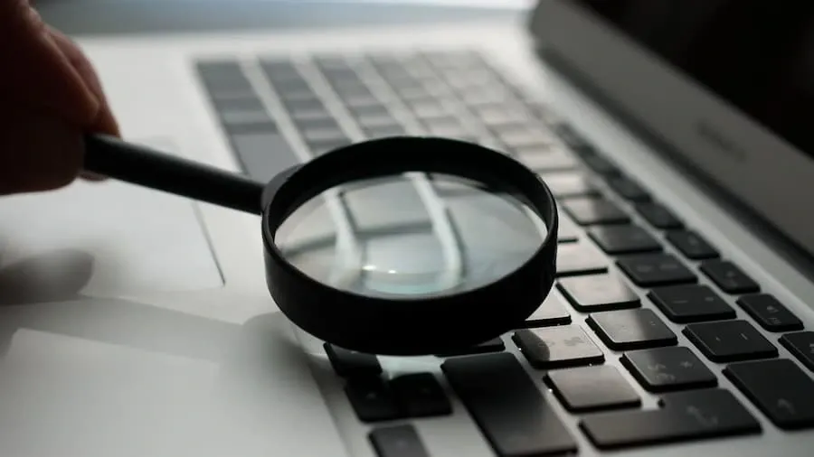 A magnifying glass examining text next to a laptop
