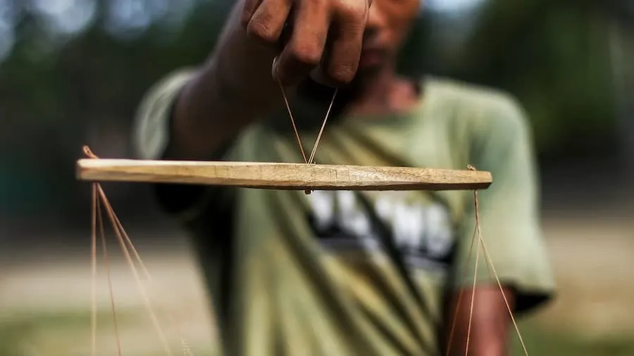 A hand holding a two-pan balance scale